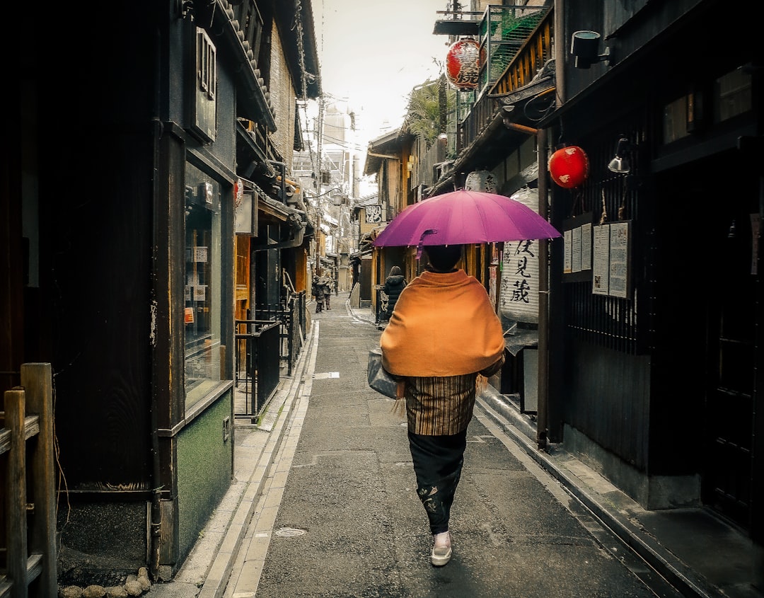woman in brown umbrella walking on sidewalk during daytime