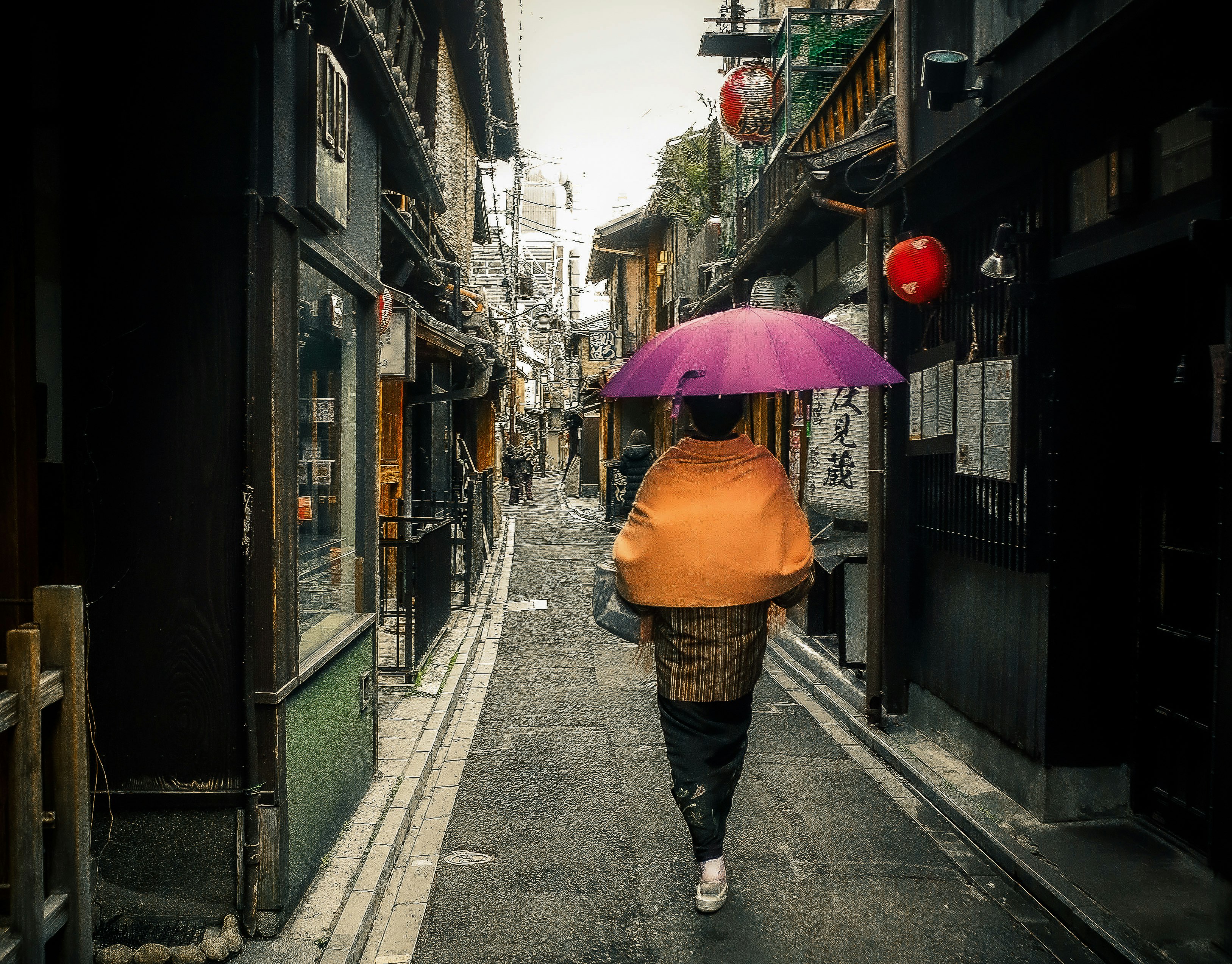 woman in brown umbrella walking on sidewalk during daytime