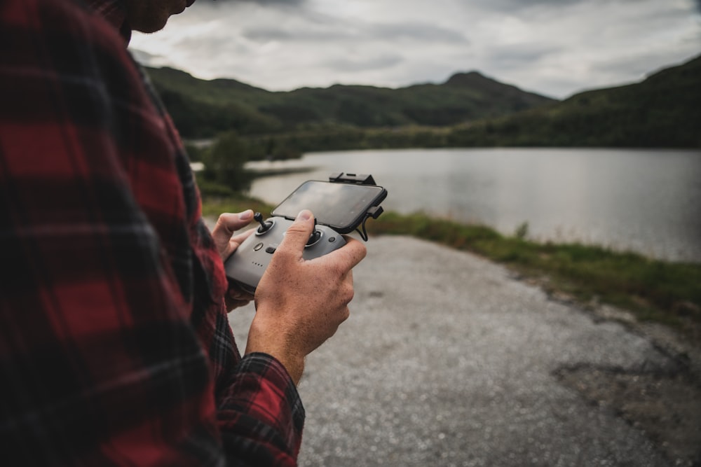 man in red and black jacket holding silver smartphone