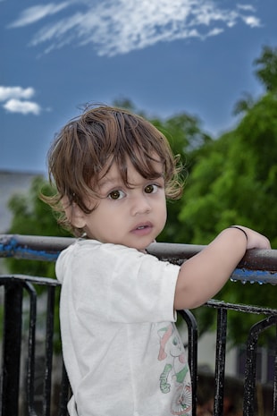 girl in white shirt standing on black metal railings during daytime