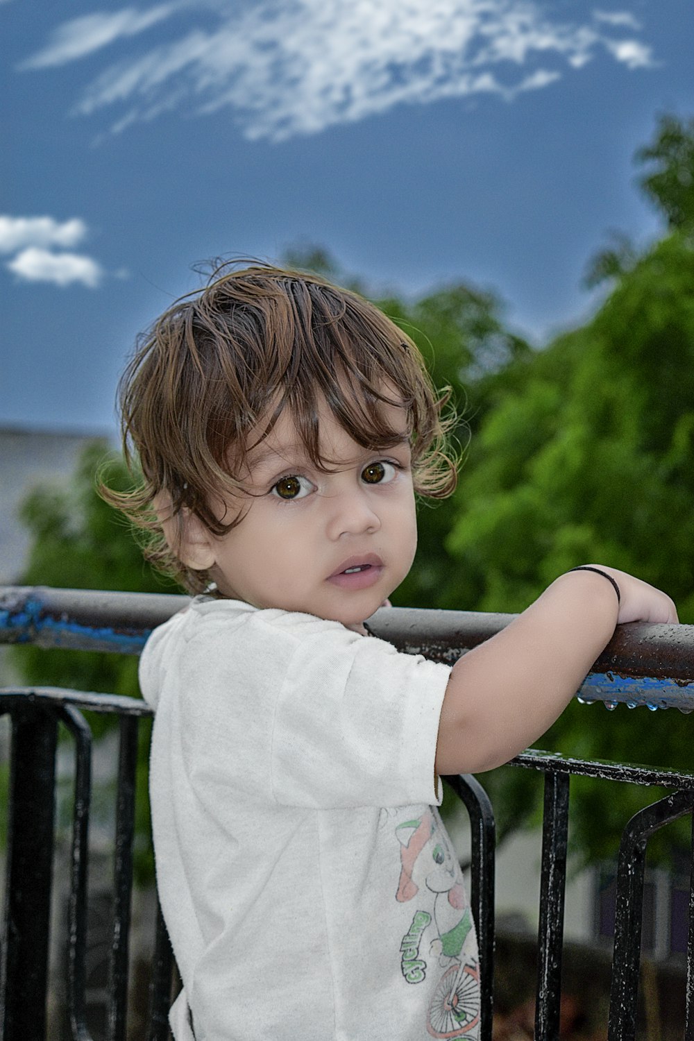 girl in white shirt standing on black metal railings during daytime