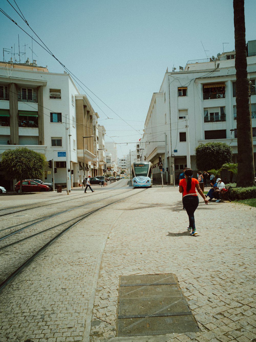 people walking on sidewalk near white concrete building during daytime