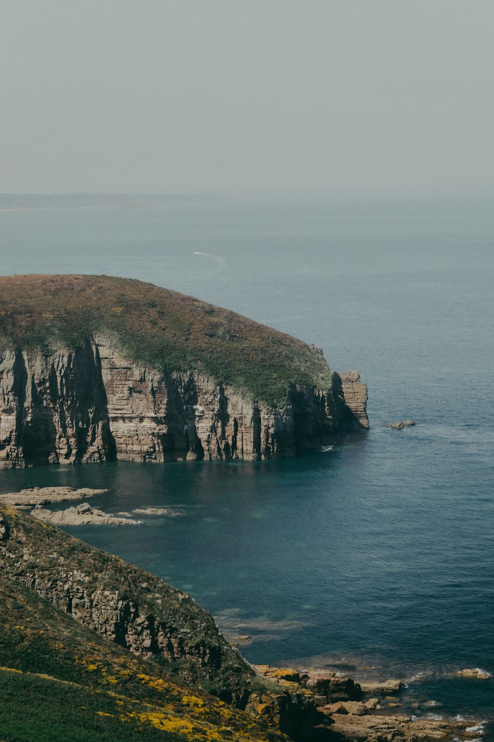 brown and green rock formation beside sea during daytime