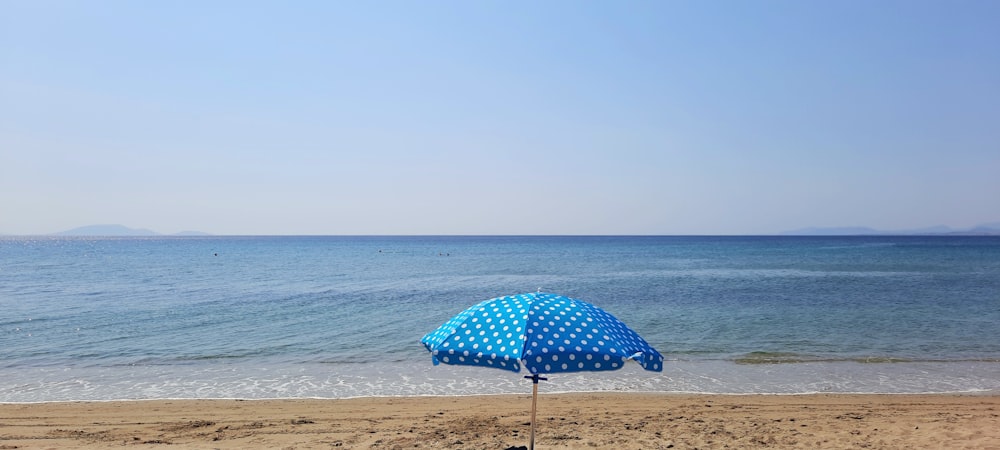 sombrilla azul en la playa durante el día