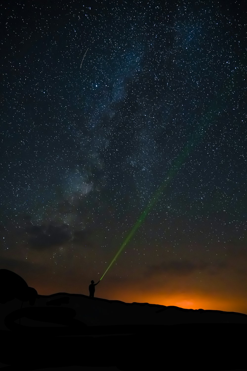silhouette of man standing on rock under starry night