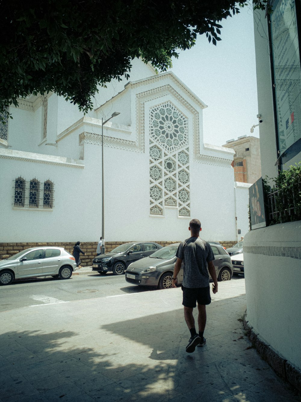 man in blue t-shirt walking on sidewalk during daytime