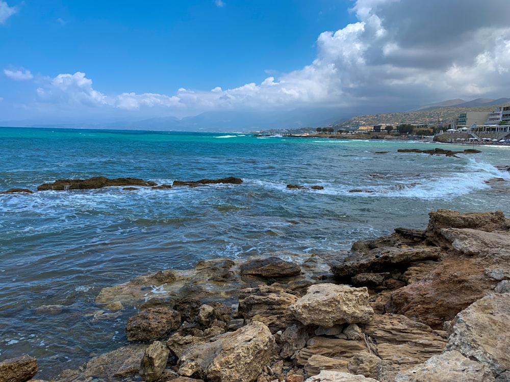 rocky shore under blue sky and white clouds during daytime