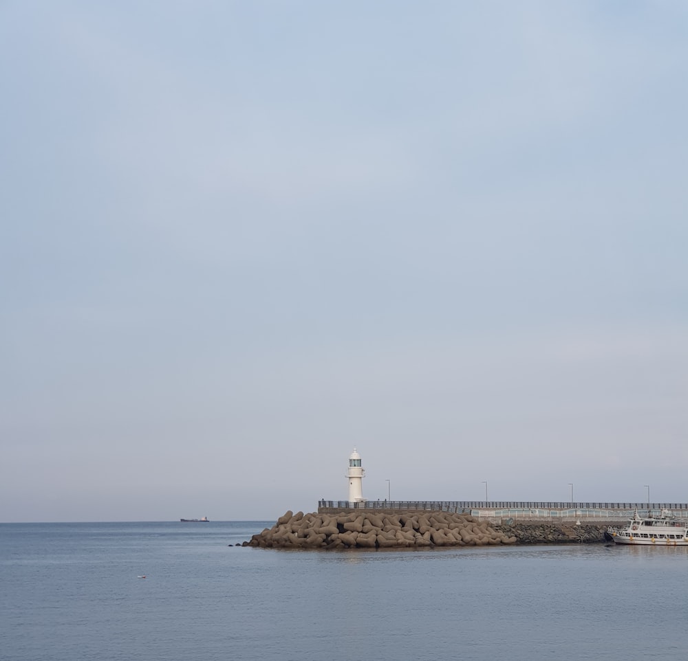 white lighthouse on brown rock formation near sea under white sky during daytime