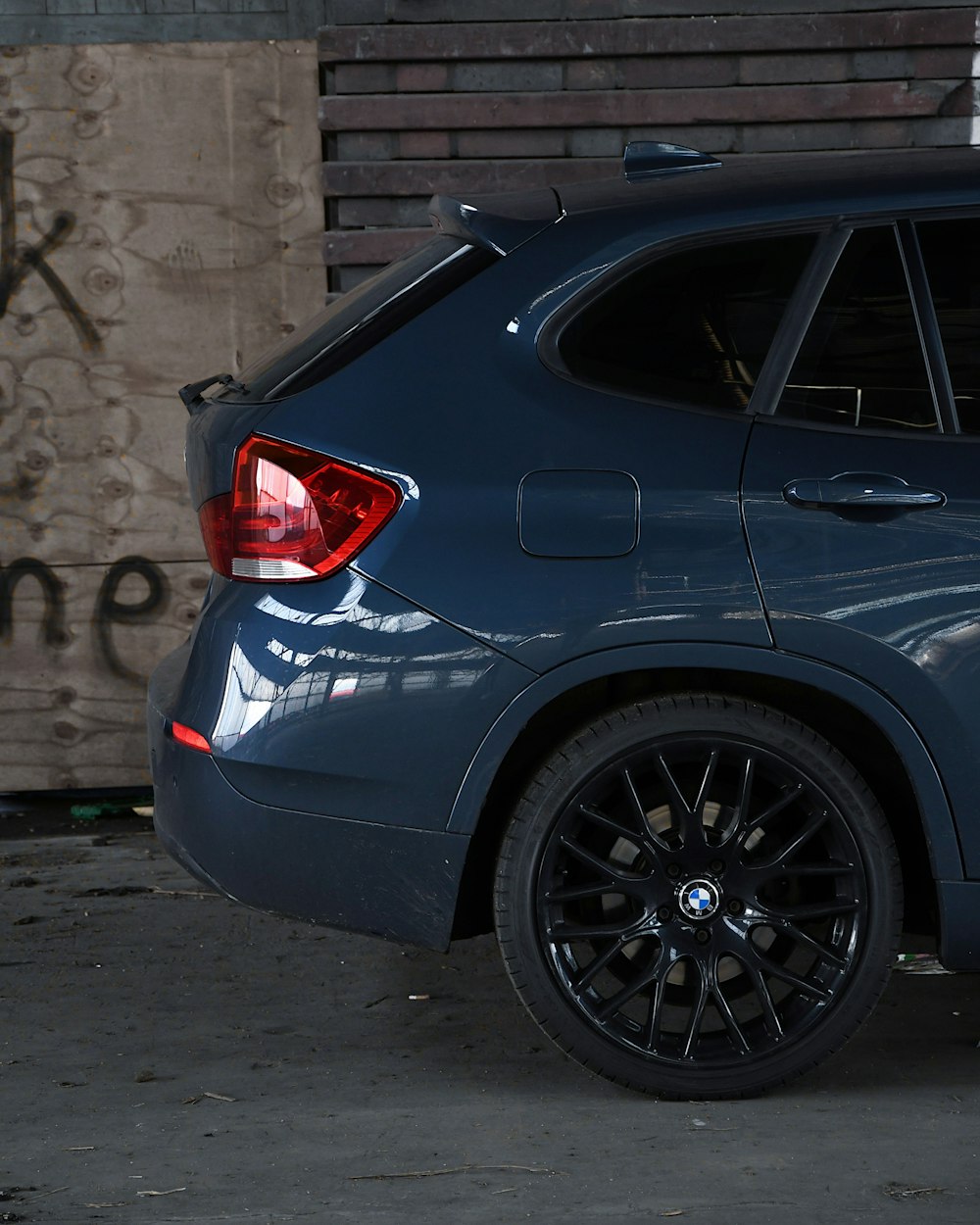 black car parked beside brown brick wall