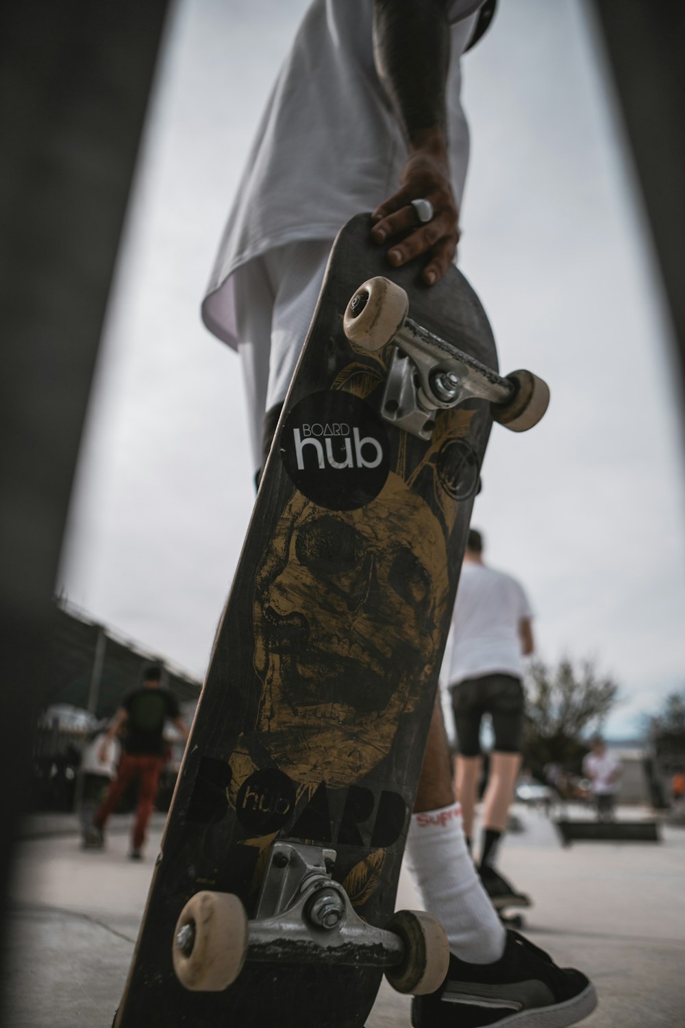 hombre con camisa blanca sosteniendo una patineta marrón y negra