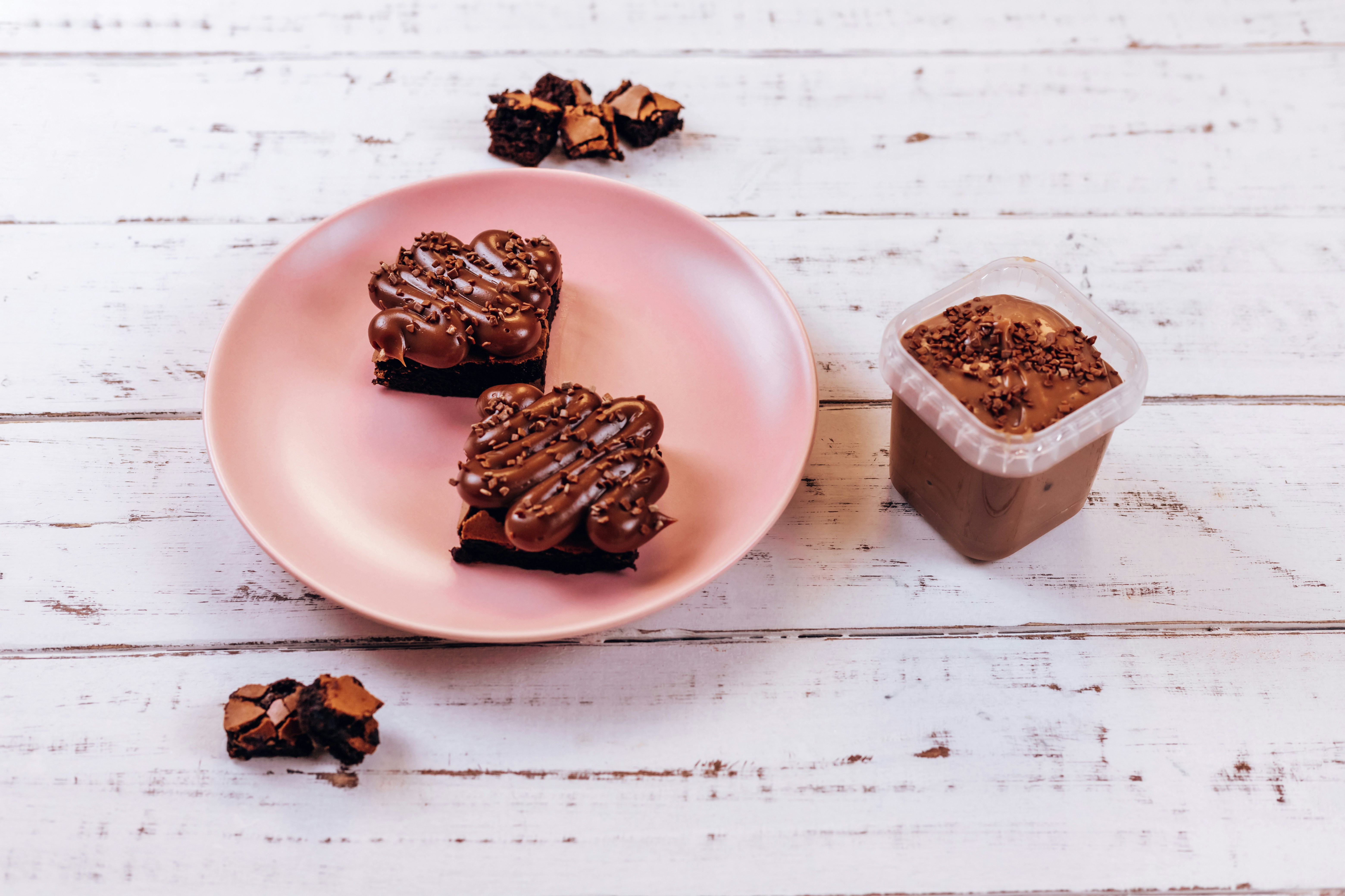 Un plato rosa cubierto con trozos de pastel junto a una taza de café