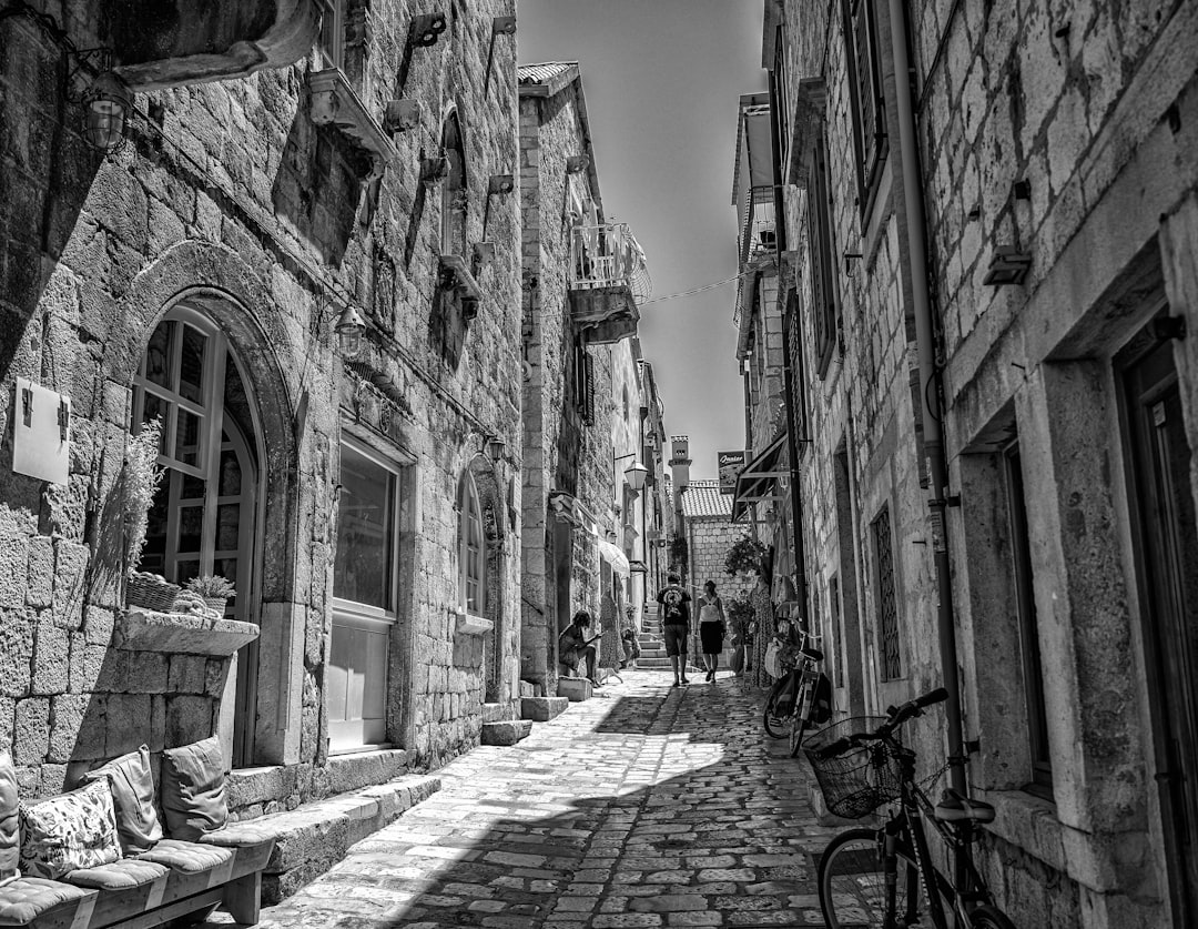 grayscale photo of bicycle parked beside building