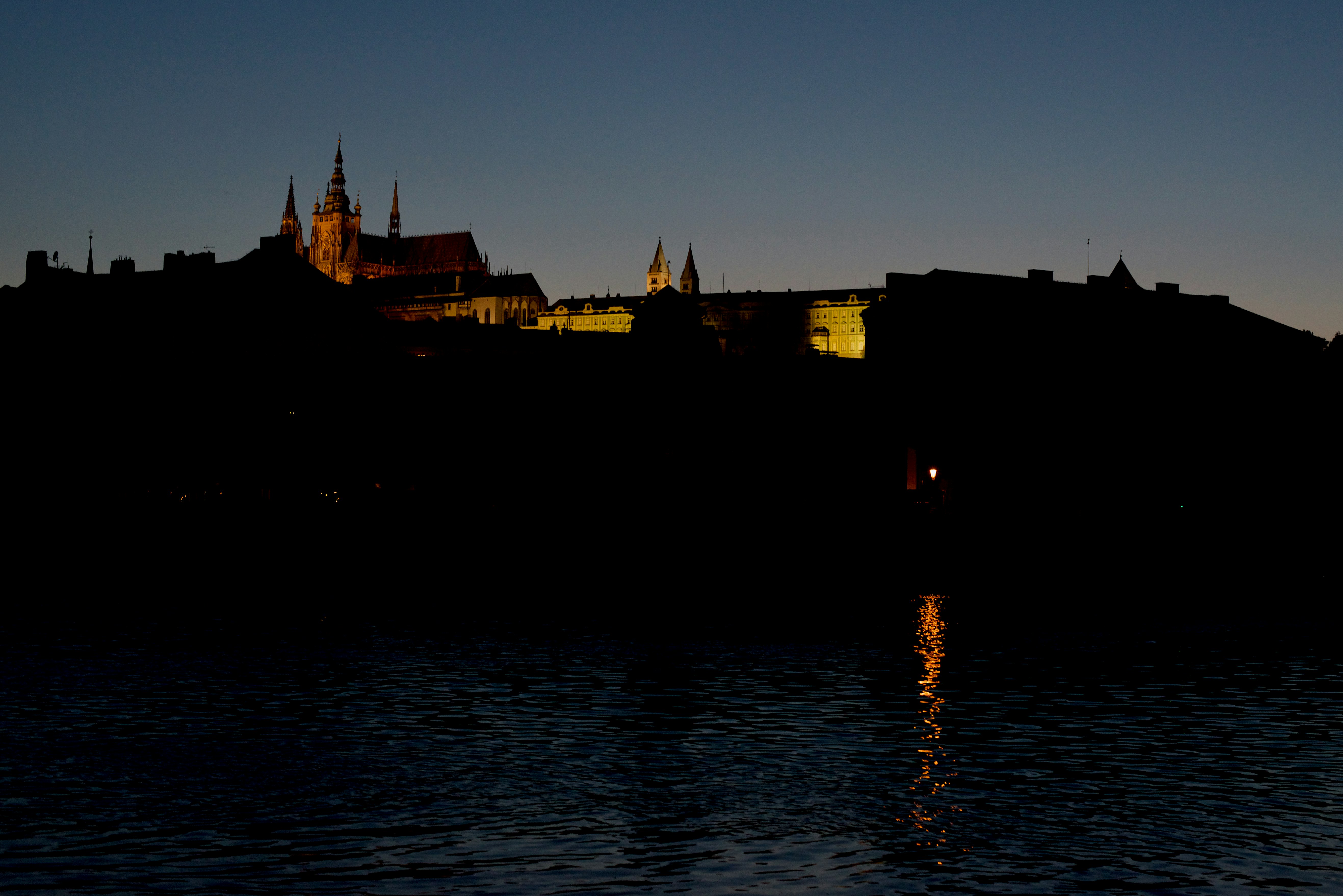 silhouette of building near body of water during sunset