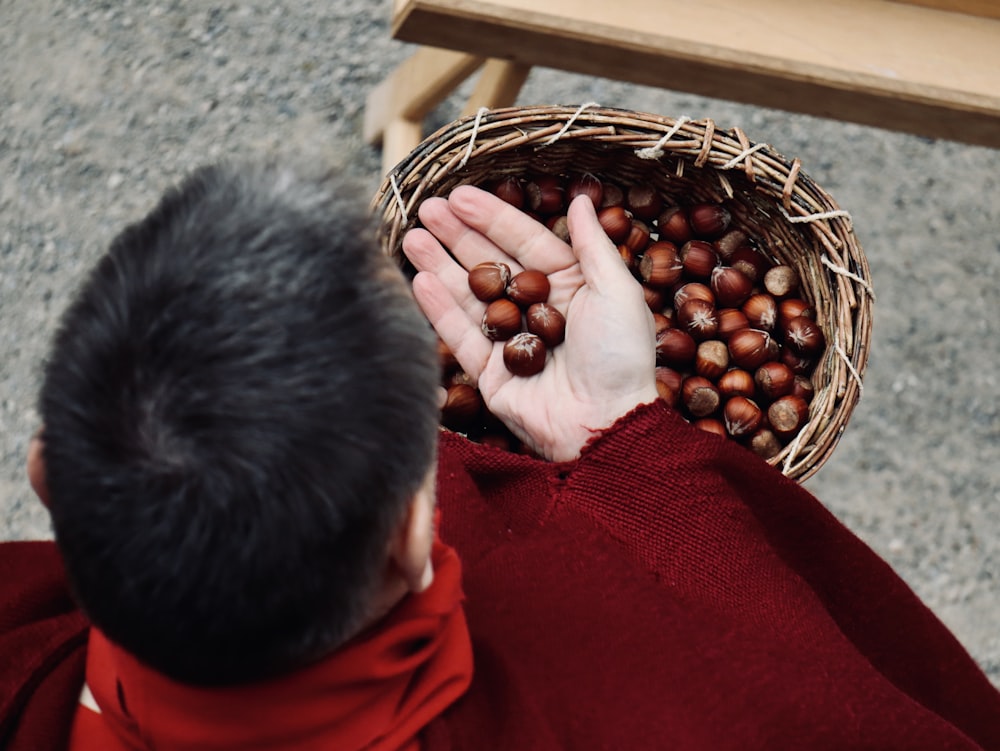 person in red sweater holding brown woven basket