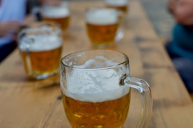 clear glass mug with beer on brown wooden table