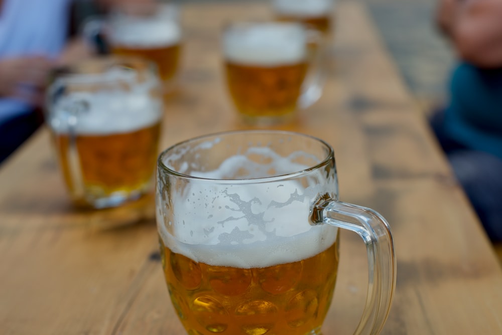 clear glass mug with beer on brown wooden table