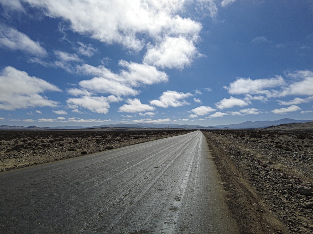 gray road under blue sky and white clouds during daytime