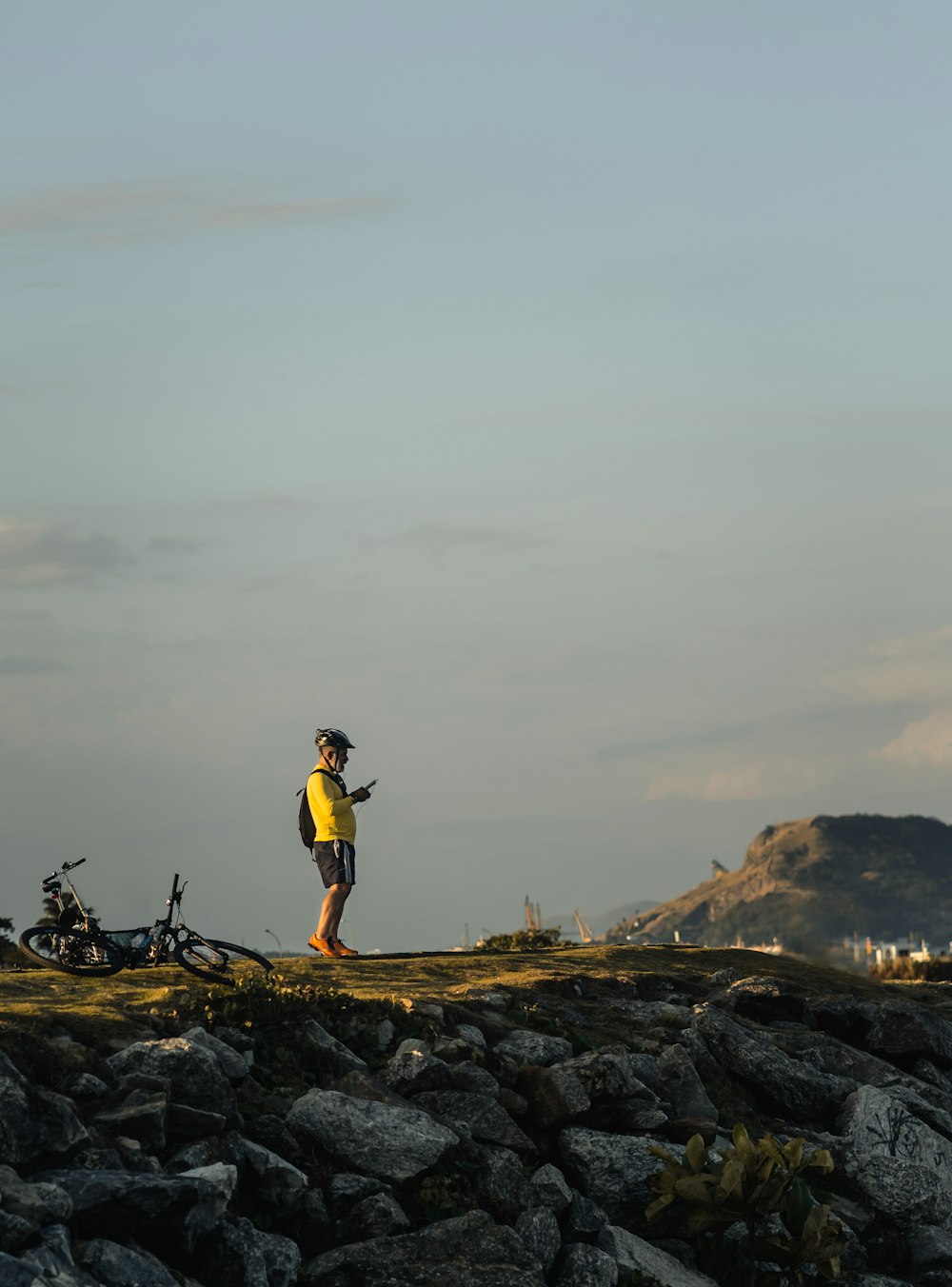 man in yellow shirt and black shorts standing on rock formation during daytime