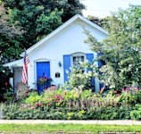 Coastal cottage exterior with bright blue shutters and a blooming flower garden