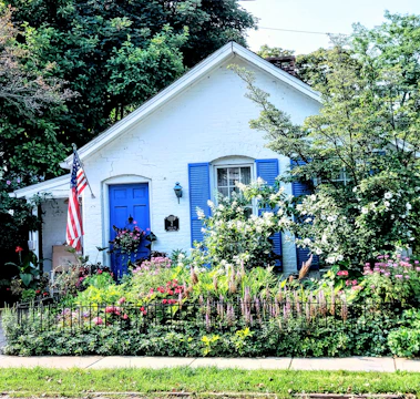 Coastal cottage exterior with bright blue shutters and a blooming flower garden
