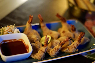 Golden fried shrimp stacked high on a plate next to a colorful coleslaw.