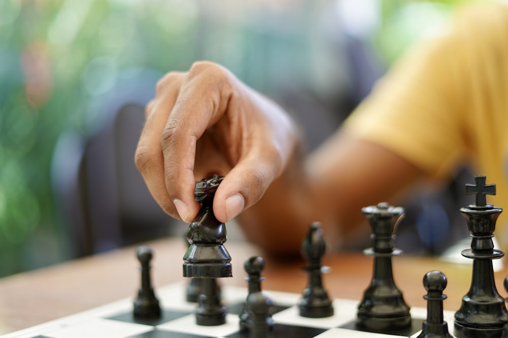 person holding black and silver chess piece