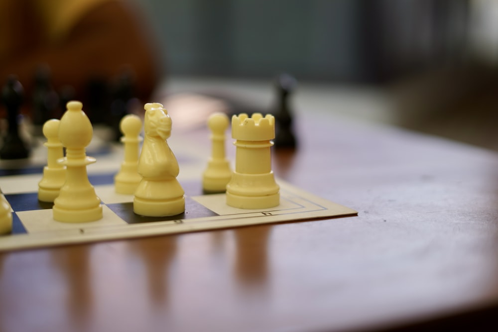 Pezzo degli scacchi di plastica gialla su tavolo bianco