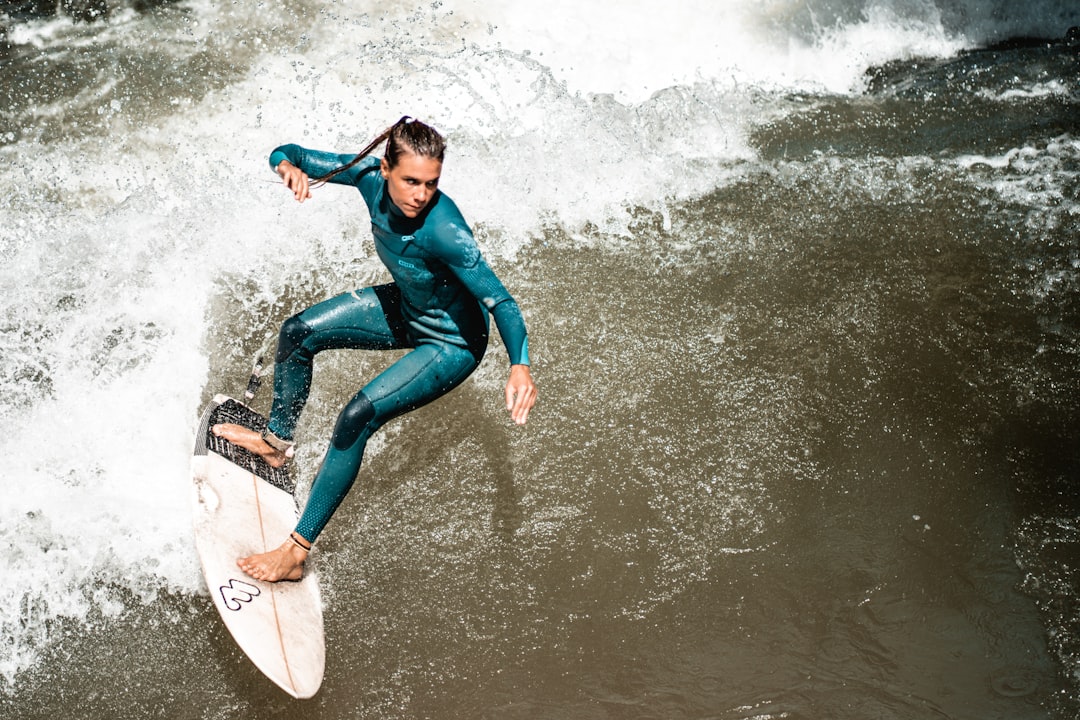 woman in blue long sleeve shirt and blue denim jeans surfing on water during daytime