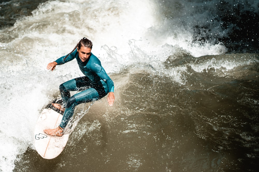 uomo in camicia blu a maniche lunghe e jeans blu denim che fa surf sull'acqua durante il giorno