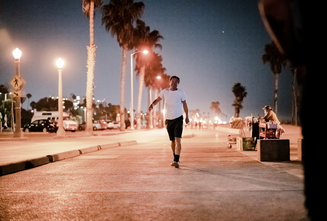 man in black t-shirt and black shorts running on street during night time
