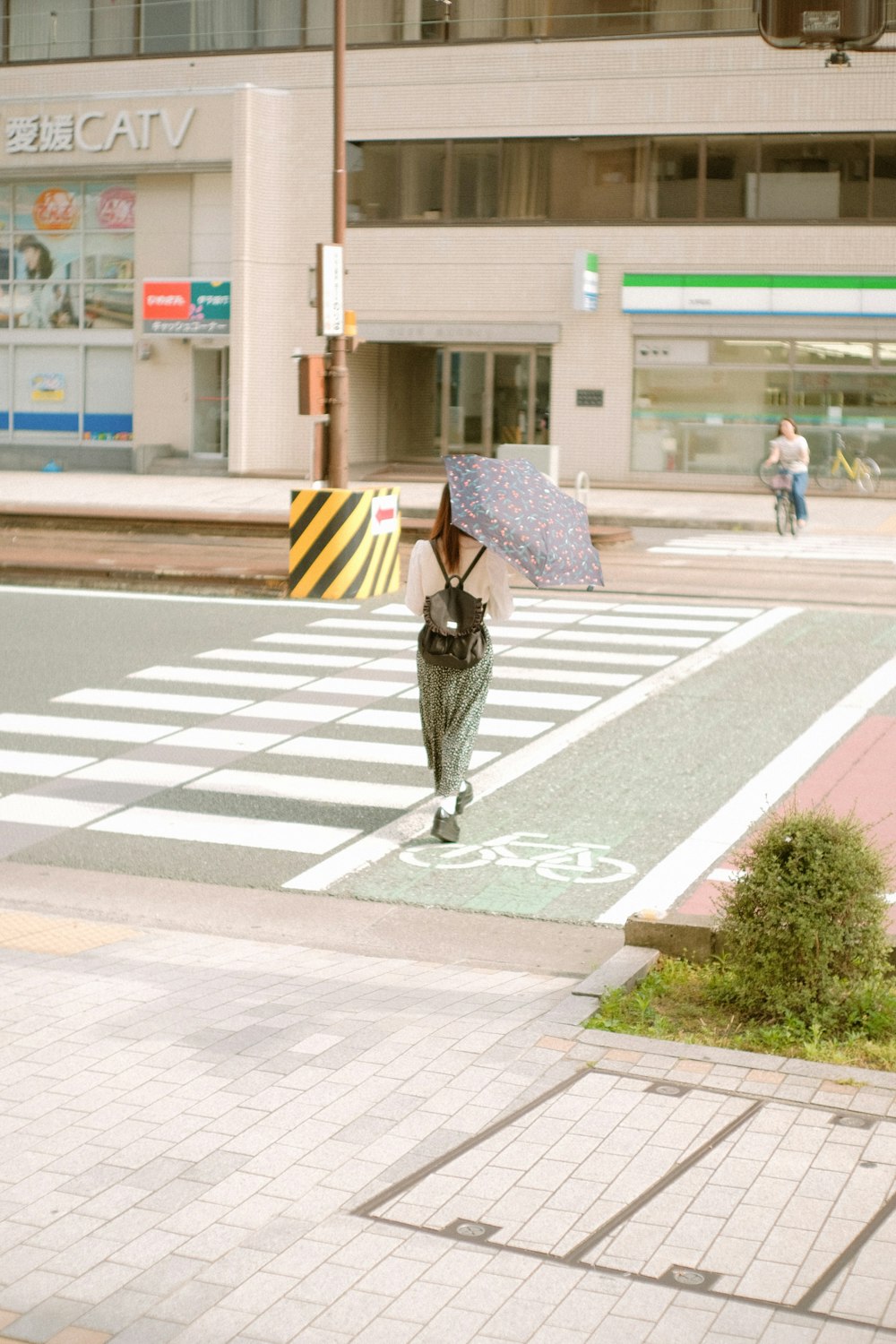woman in black jacket and black pants holding umbrella walking on pedestrian lane during daytime