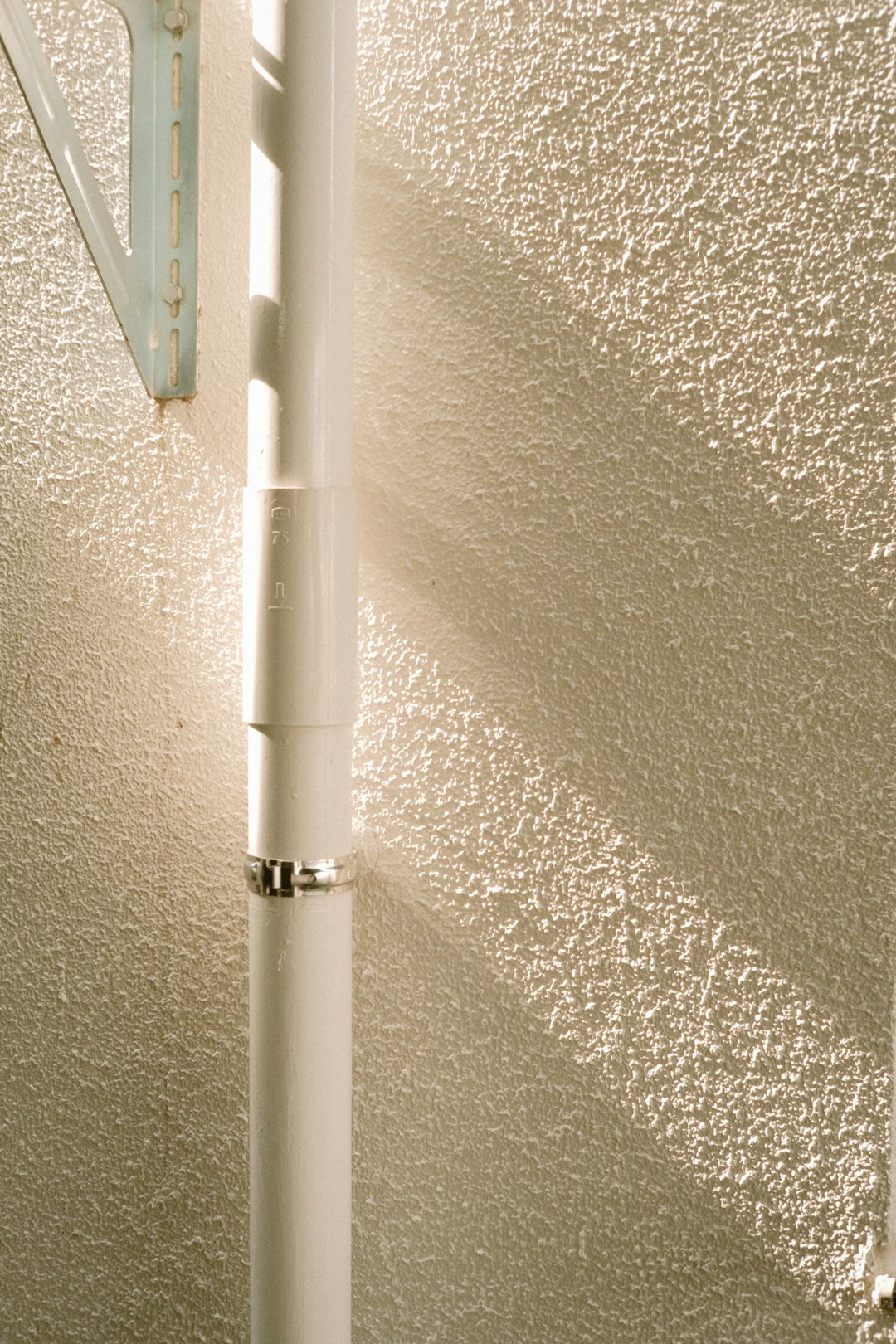 white metal pipe on white concrete wall