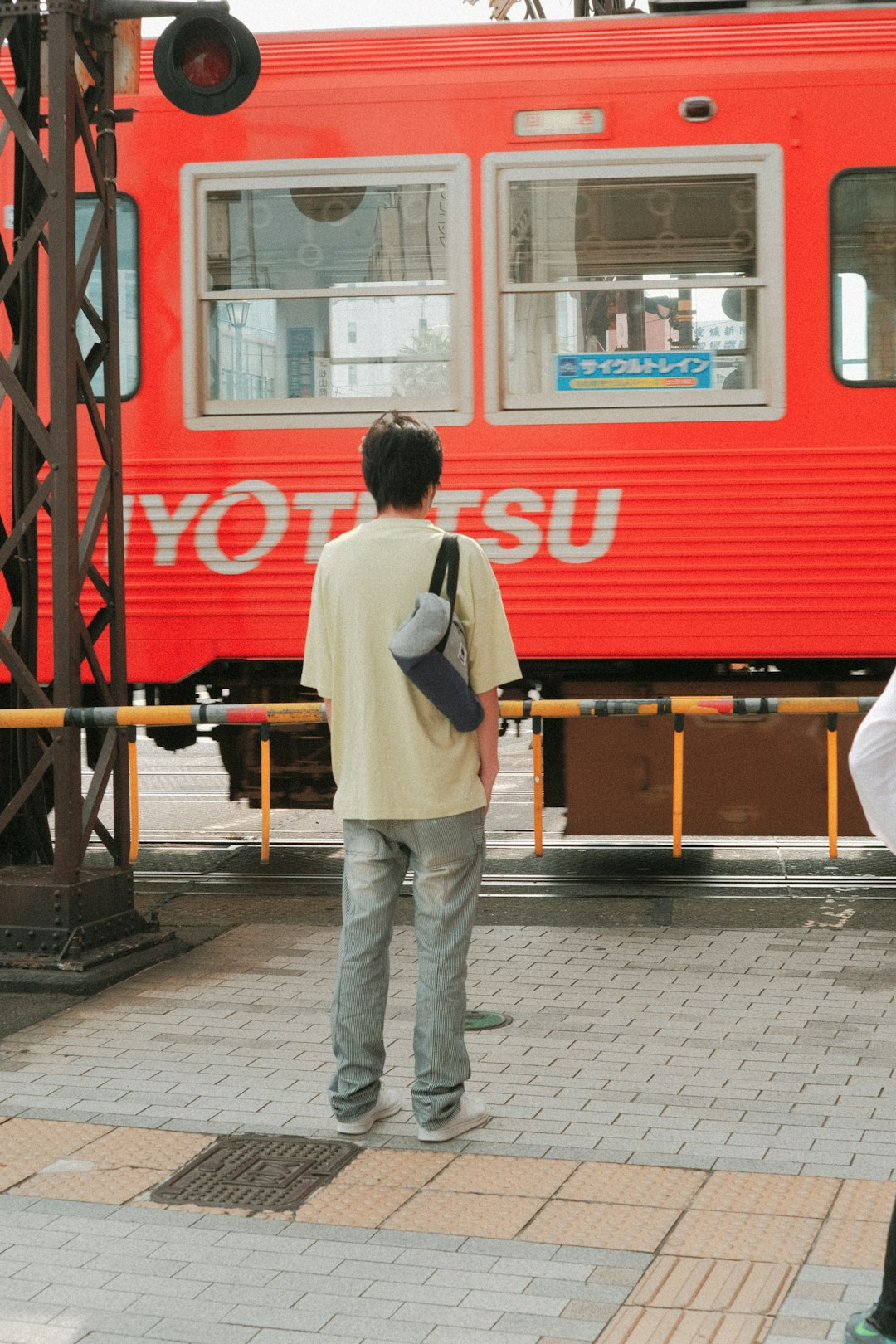 man in white long sleeve shirt and gray pants standing near red train during daytime