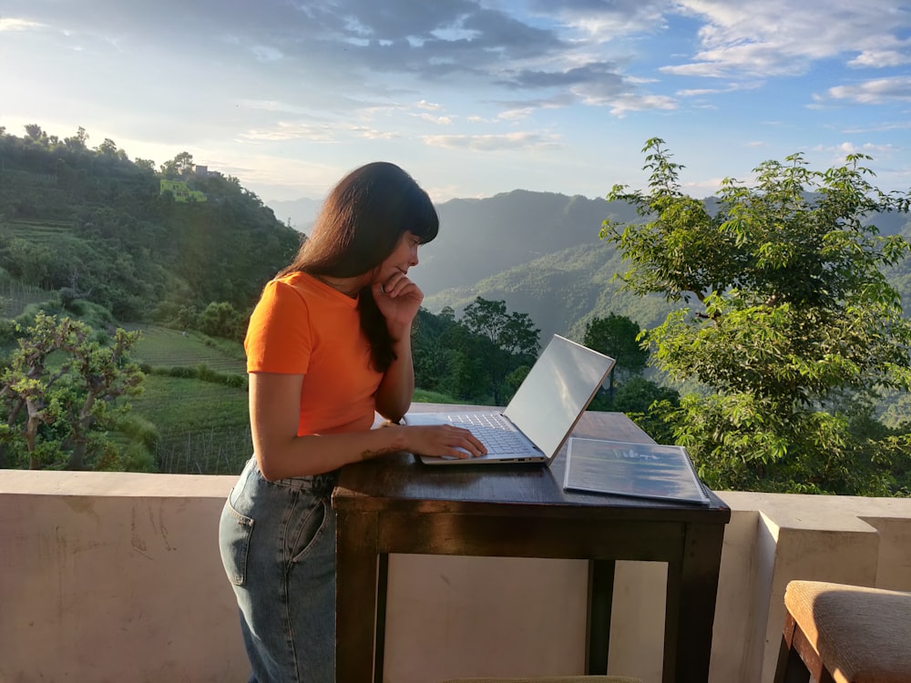 woman in orange shirt sitting on white chair reading book