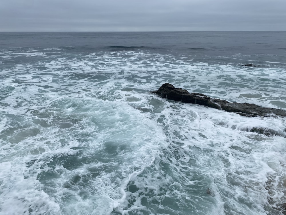 ocean waves crashing on brown rock formation during daytime