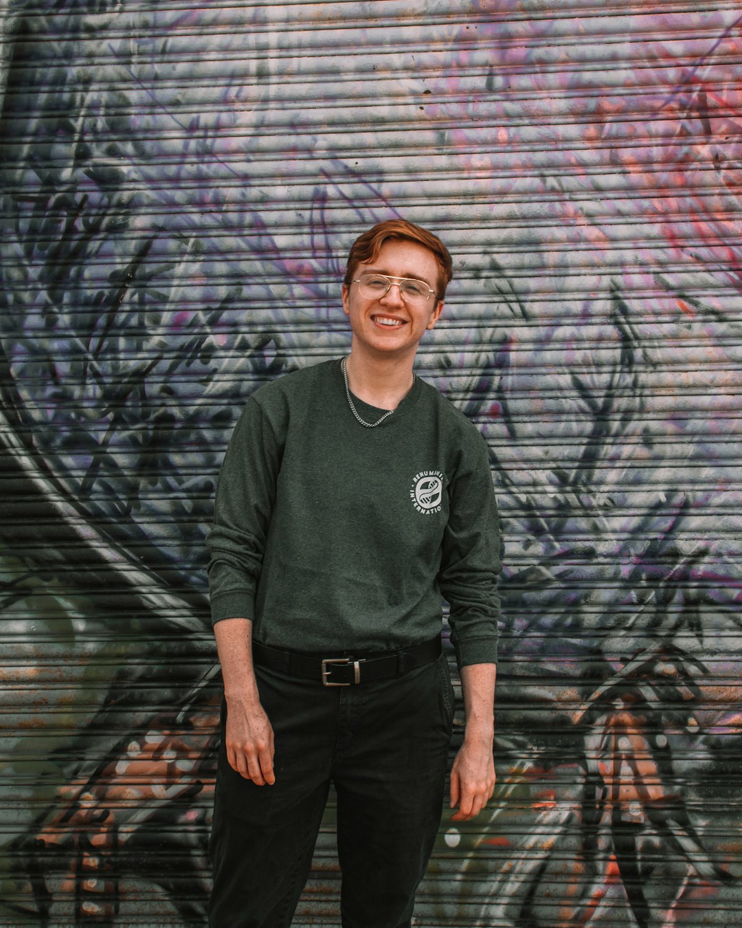 man in green nike crew neck sweater standing beside graffiti wall