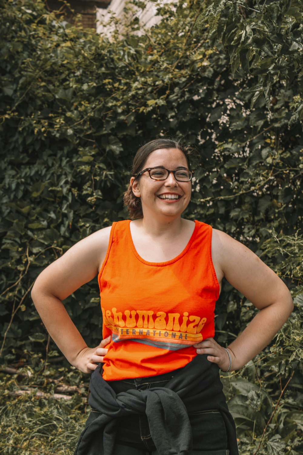 woman in orange tank top and red shorts smiling