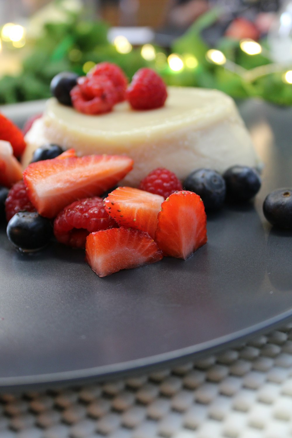 sliced strawberries and blueberries on black round plate