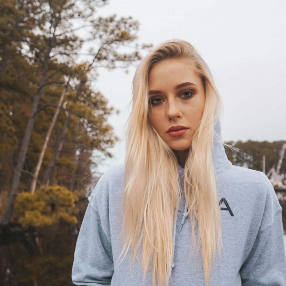 woman in gray long sleeve shirt standing near trees during daytime