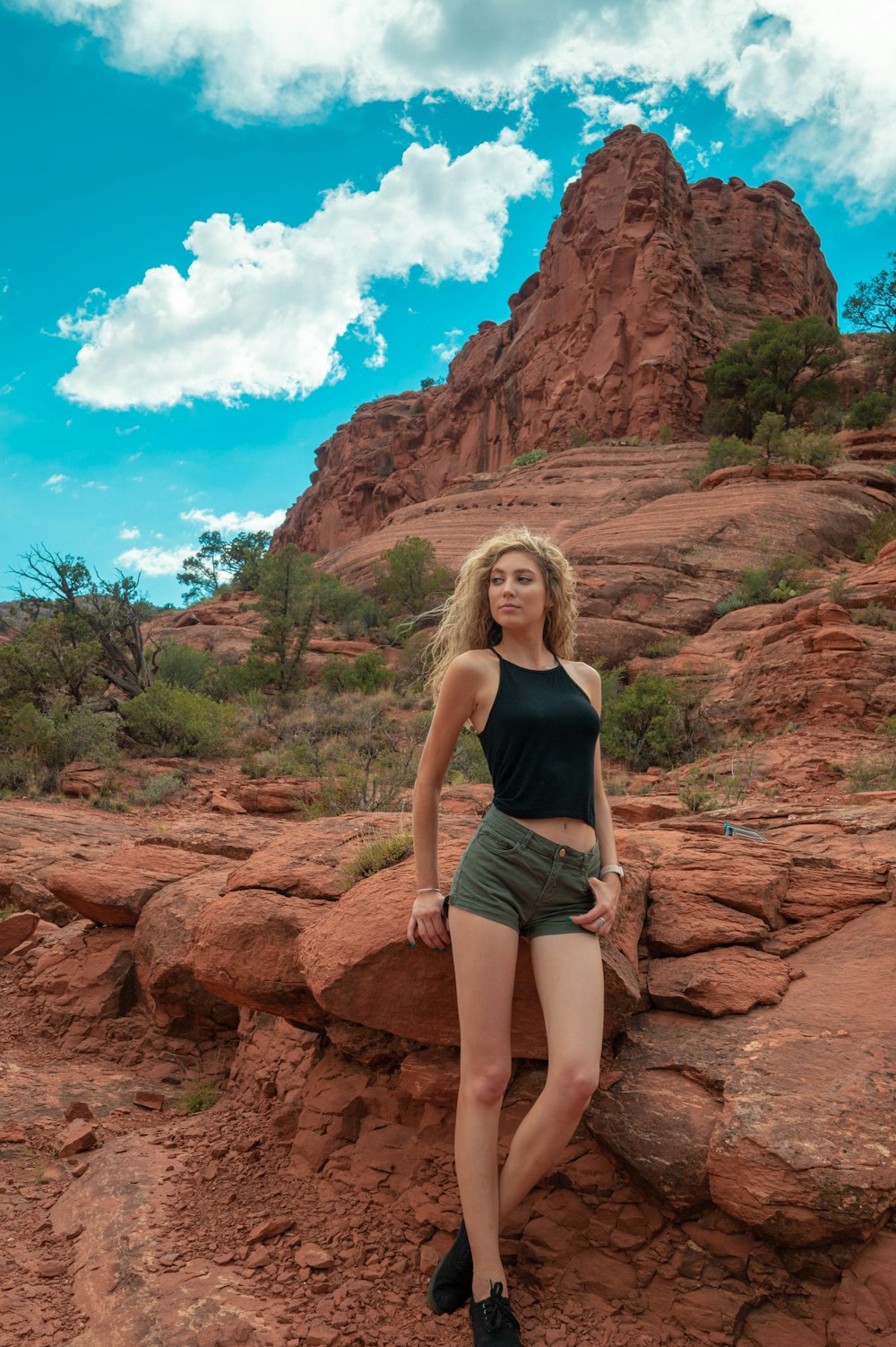 woman in black tank top and black shorts standing on brown rock formation during daytime