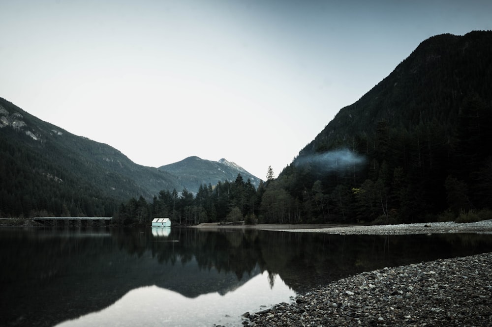 body of water near green trees and mountain during daytime