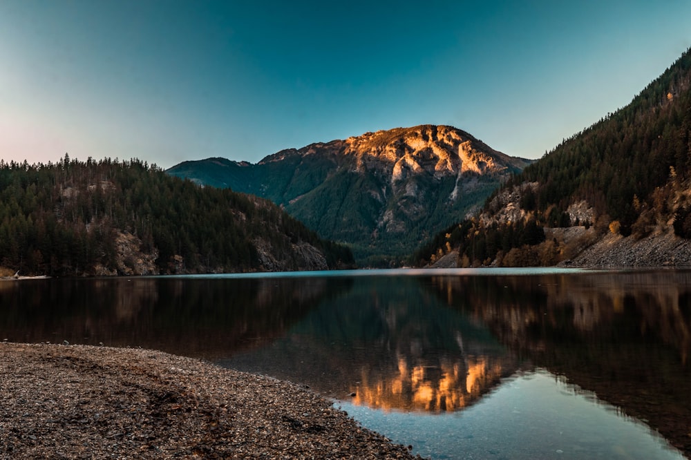 lake near mountain under blue sky during daytime