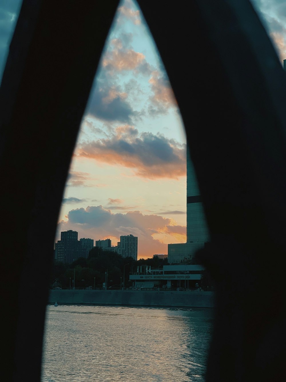 silhouette of city buildings near body of water during sunset