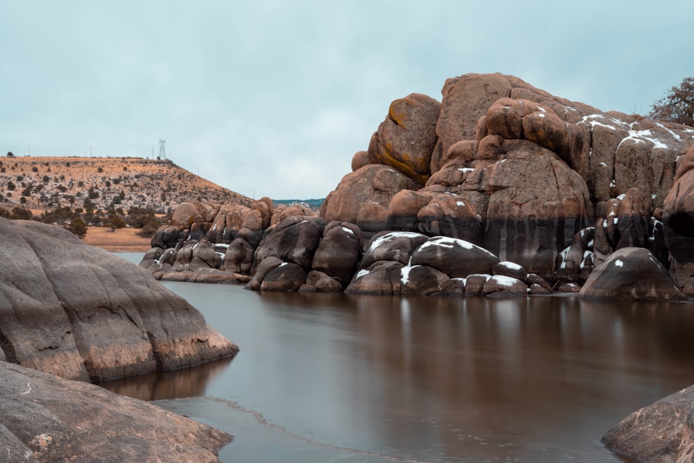 brown rock formation beside body of water during daytime