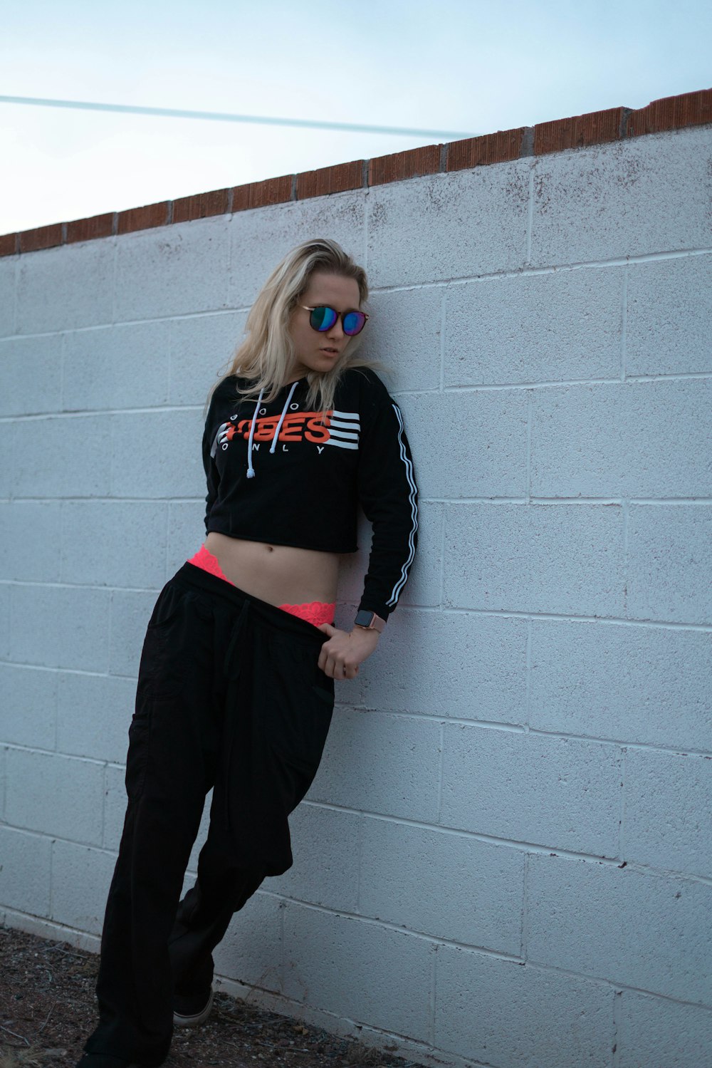 woman in black and white striped long sleeve shirt and black pants standing beside gray concrete