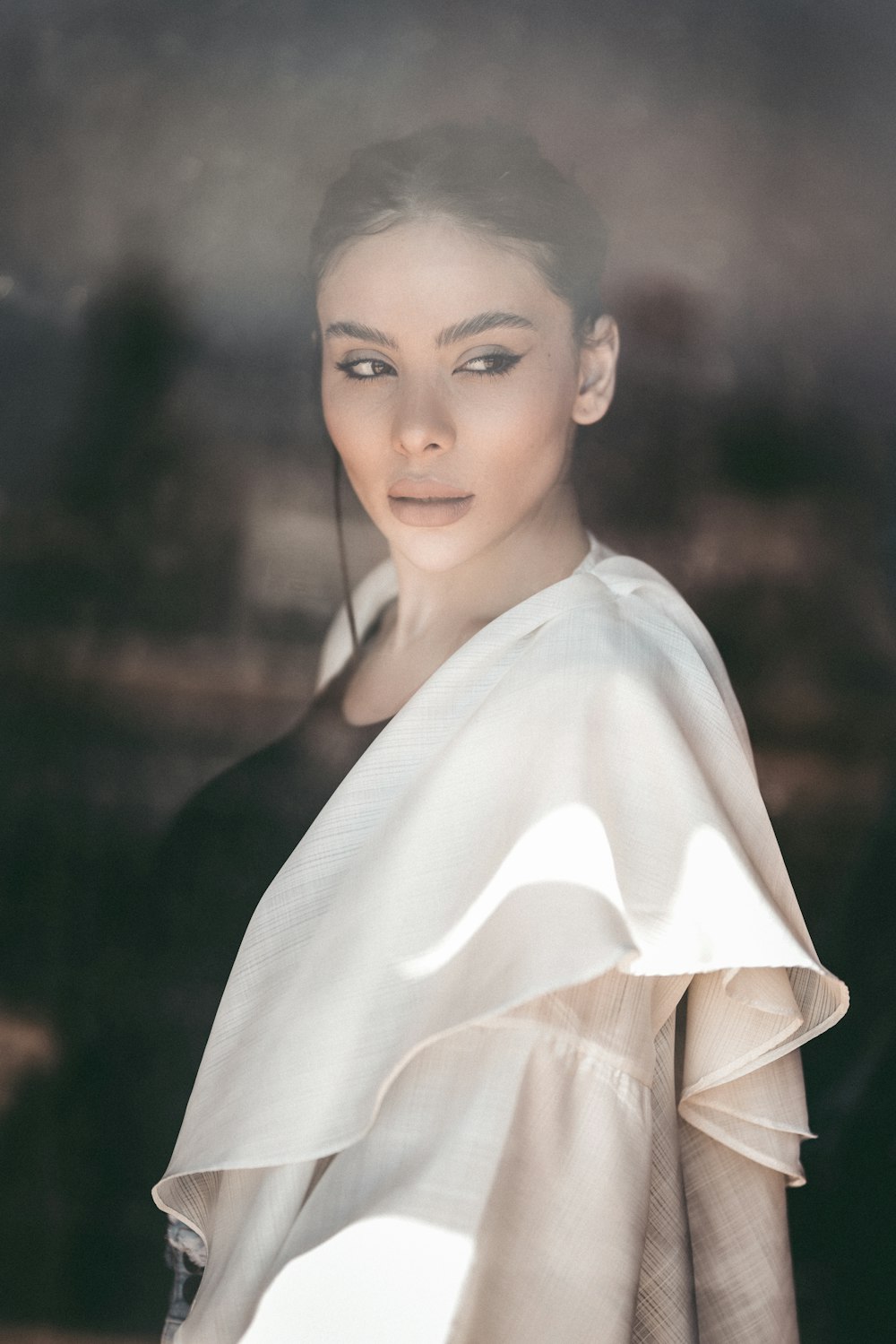 a woman standing in front of a window wearing a white shawl