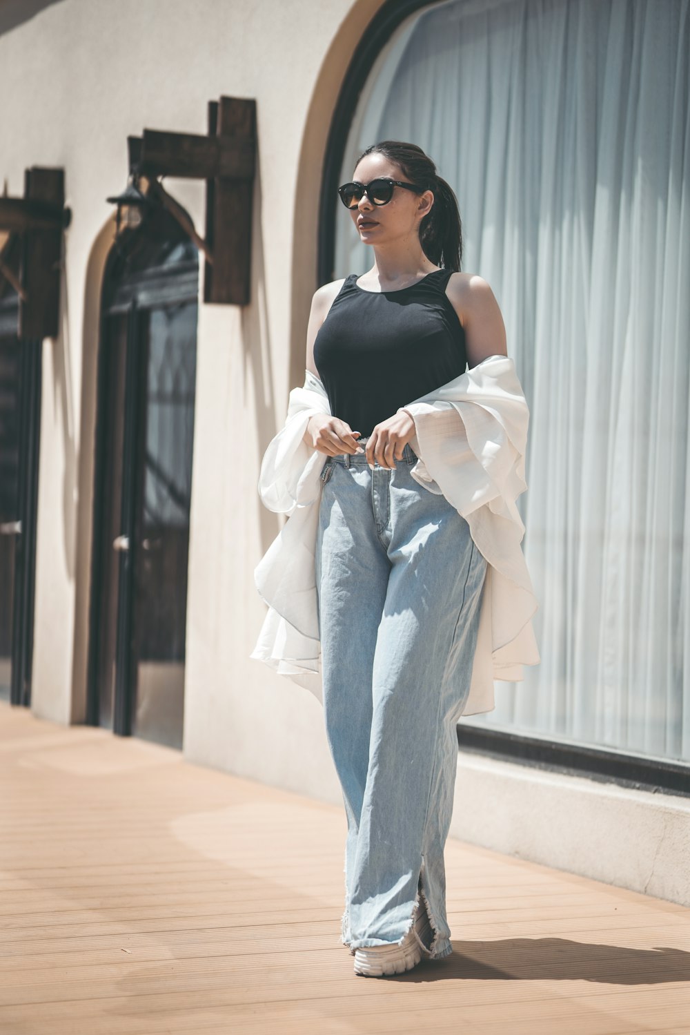 woman in black tank top and blue denim jeans wearing black sunglasses