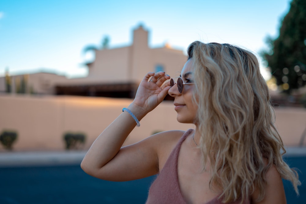 woman in blue tank top holding her face