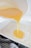 A mixture of what appears to be beaten eggs is being poured from a white bowl into a white rectangular baking dish that contains an unbaked dough base. A gray and white striped kitchen towel is partially visible at the bottom of the image.