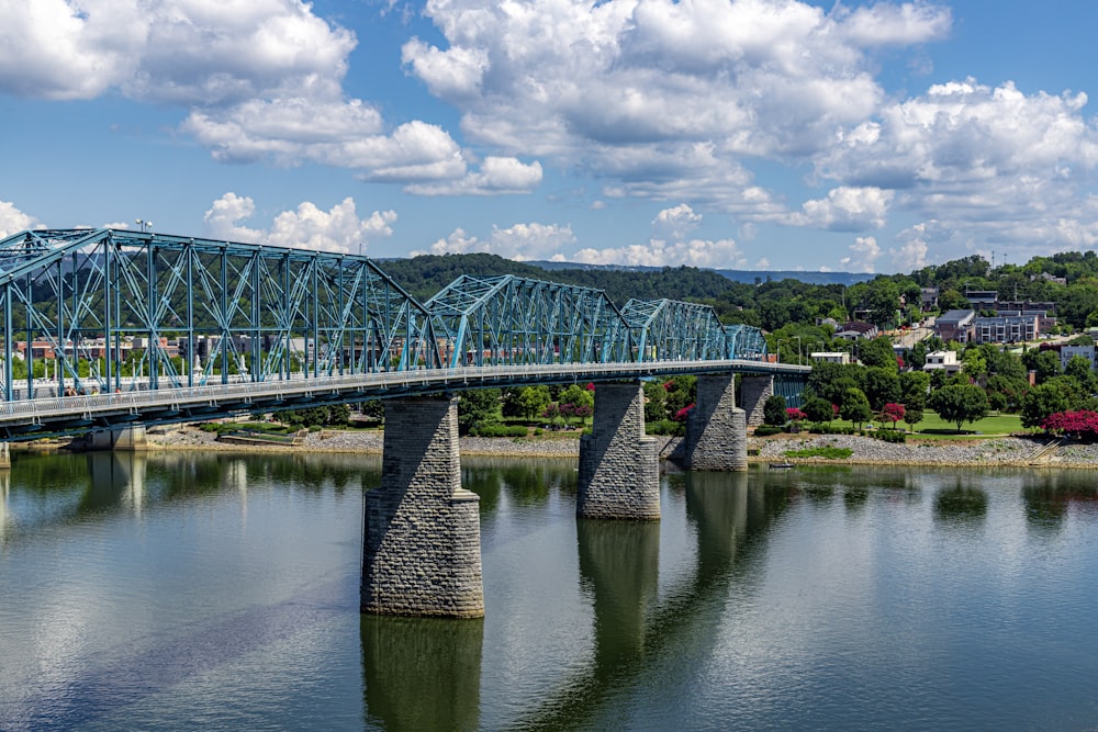 green metal bridge over river under blue sky and white clouds during daytime